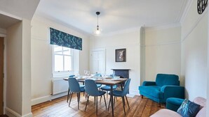 Un coin repas avec une table et des chaises en bois, une cheminée et un canapé bleu.