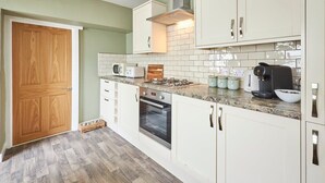 Une cuisine compacte avec des meubles blancs, un four à micro-ondes, un grille-pain, une machine à café et une cuisinière.