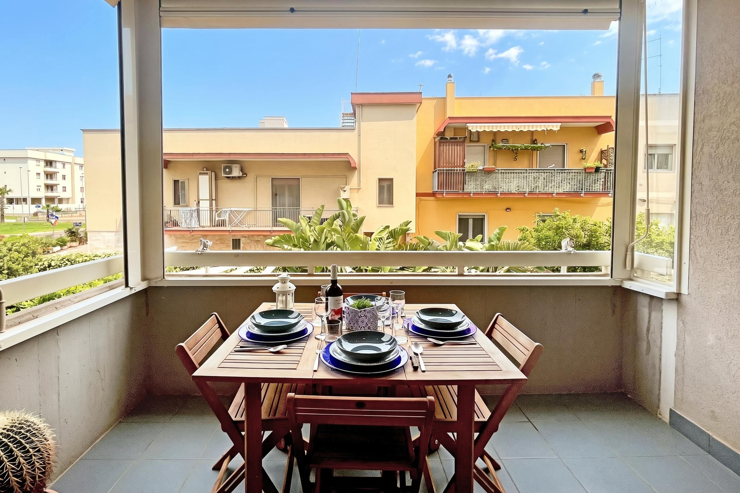 Un balcon avec une table dressée pour le dîner, donnant sur un quartier résidentiel avec des immeubles et de la verdure.