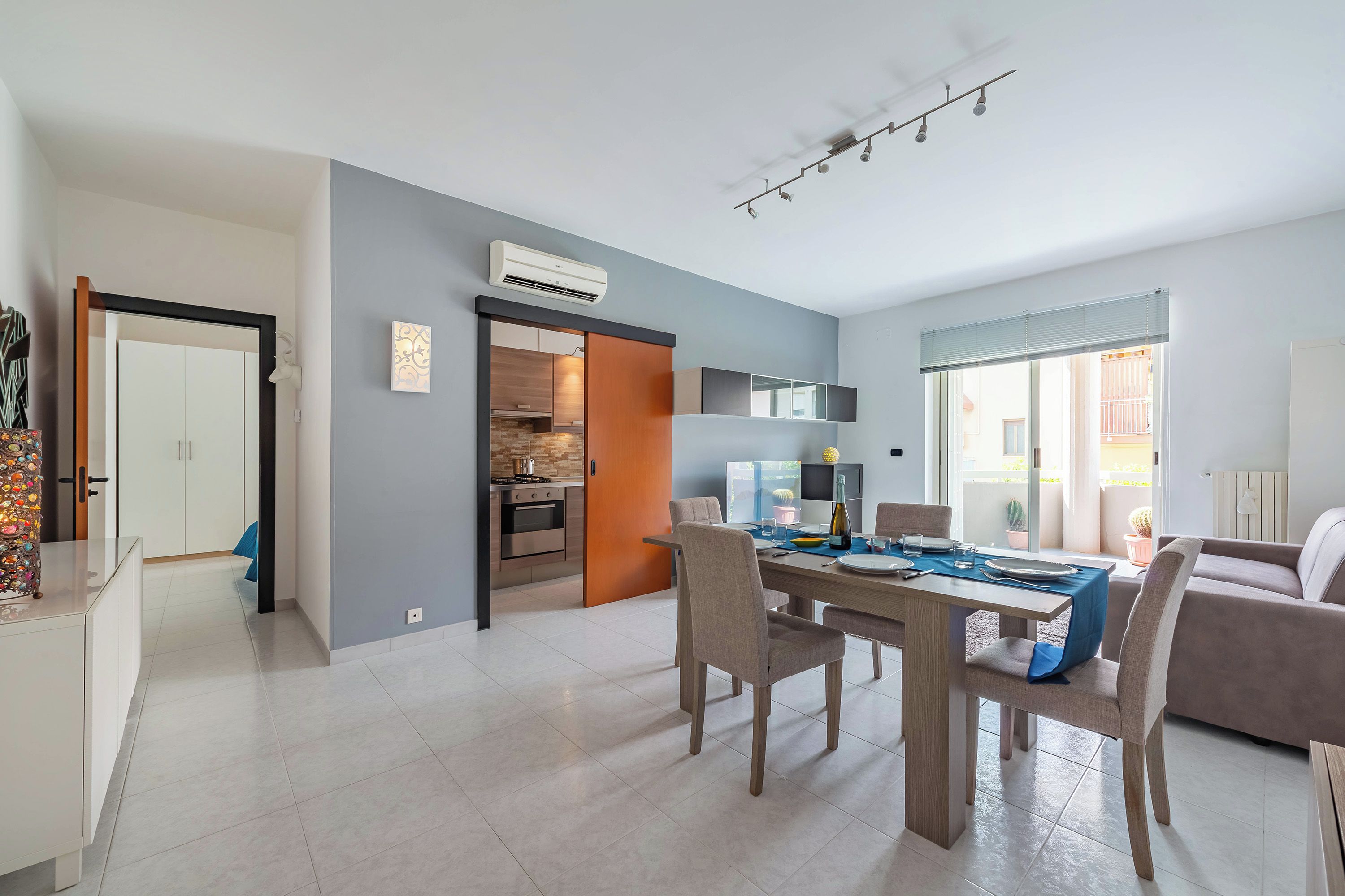 A modern living space with a dining area, kitchen, and a view to the outside.