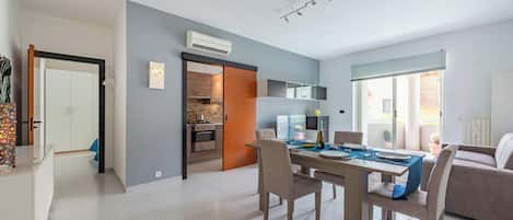 A modern living space with a dining area, kitchen, and a view to the outside.
