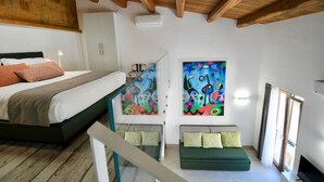 Une chambre à coucher avec un lit, un canapé, un tableau et une fenêtre.