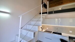 Une cuisine moderne avec un escalier blanc menant à un niveau supérieur.