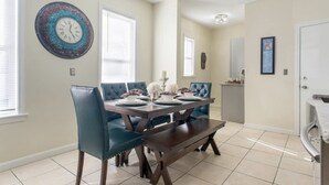 A dining room with a dark wooden table, teal upholstered chairs, and a decorative clock on the wall. - Cozy 3 bedroom - Free Parking, close to buses.  (Boston)
