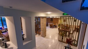 A hotel lobby with a wine rack, seating area, and an exit sign. - LILEO Hotel (Kutaisi)