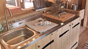 Una cocina con armarios de madera, un lavamanos de acero inoxidable y una encimera con utensilios de cocina.