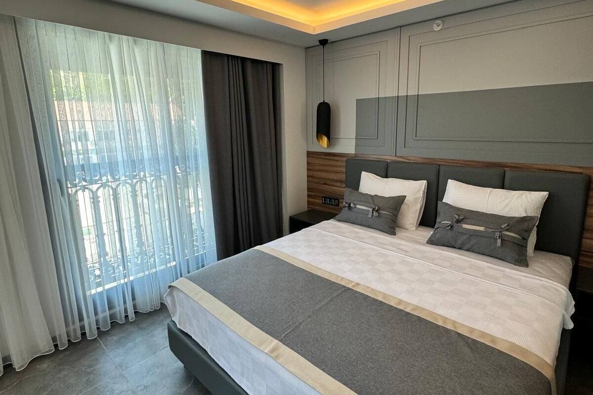A modern hotel room with a large bed, a view of the outdoors, and a minimalist design.