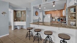 Una cocina moderna con una isla central, taburetes de bar, armarios de madera y un horno empotrado.