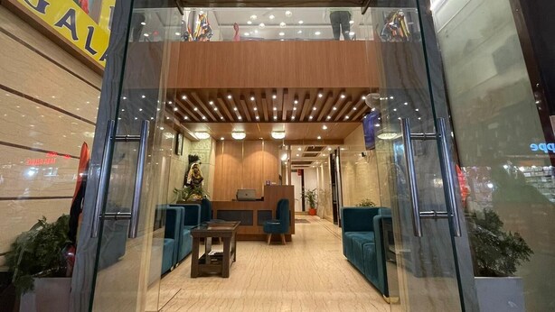 A modern hotel lobby with a reception desk, seating area, and a chandelier. - Hotel Galaxy (Reasi)