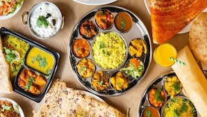 A variety of Indian dishes including rice, curries, and flatbreads on a metal plate. - Hotel Galaxy (Reasi)