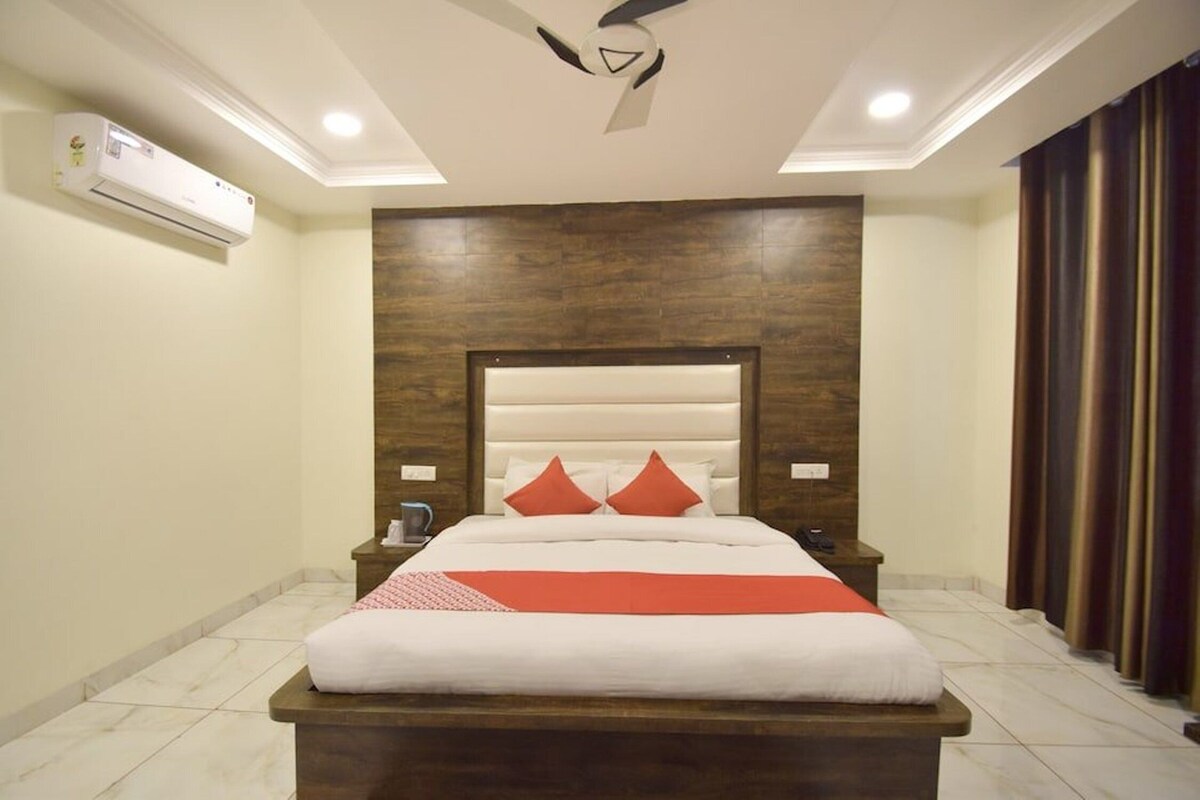 Una habitación de hotel con una cama grande, cabecero de madera y ventilador de techo.