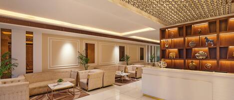 A spacious lobby with a high ceiling, a reception desk, and a seating area with sofas and a coffee table.