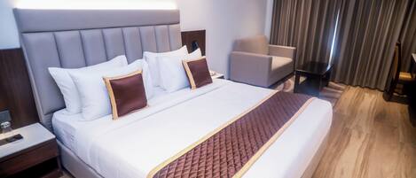 A hotel room with a large bed, a bedside table, a chair, and a curtain.