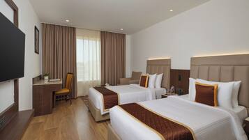A hotel room with two beds, a desk, a chair, and a television.