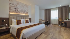 A modern hotel room with a large bed, a desk, a chair, and a view of the outdoors. - Regenta Place Gwalior (Gwalior)