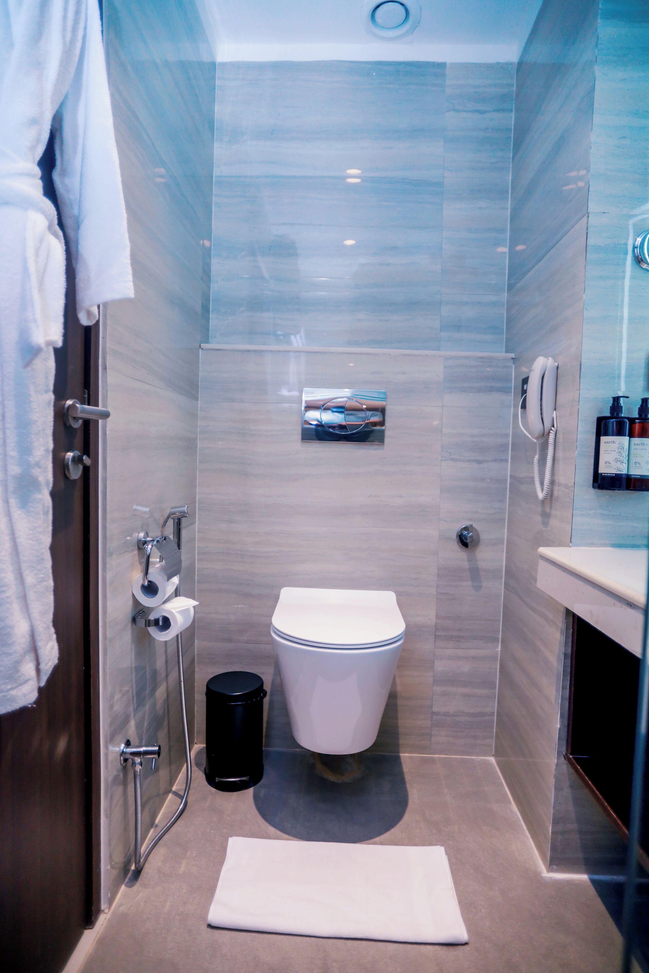 A modern bathroom with a toilet, shower, and a towel rack.
