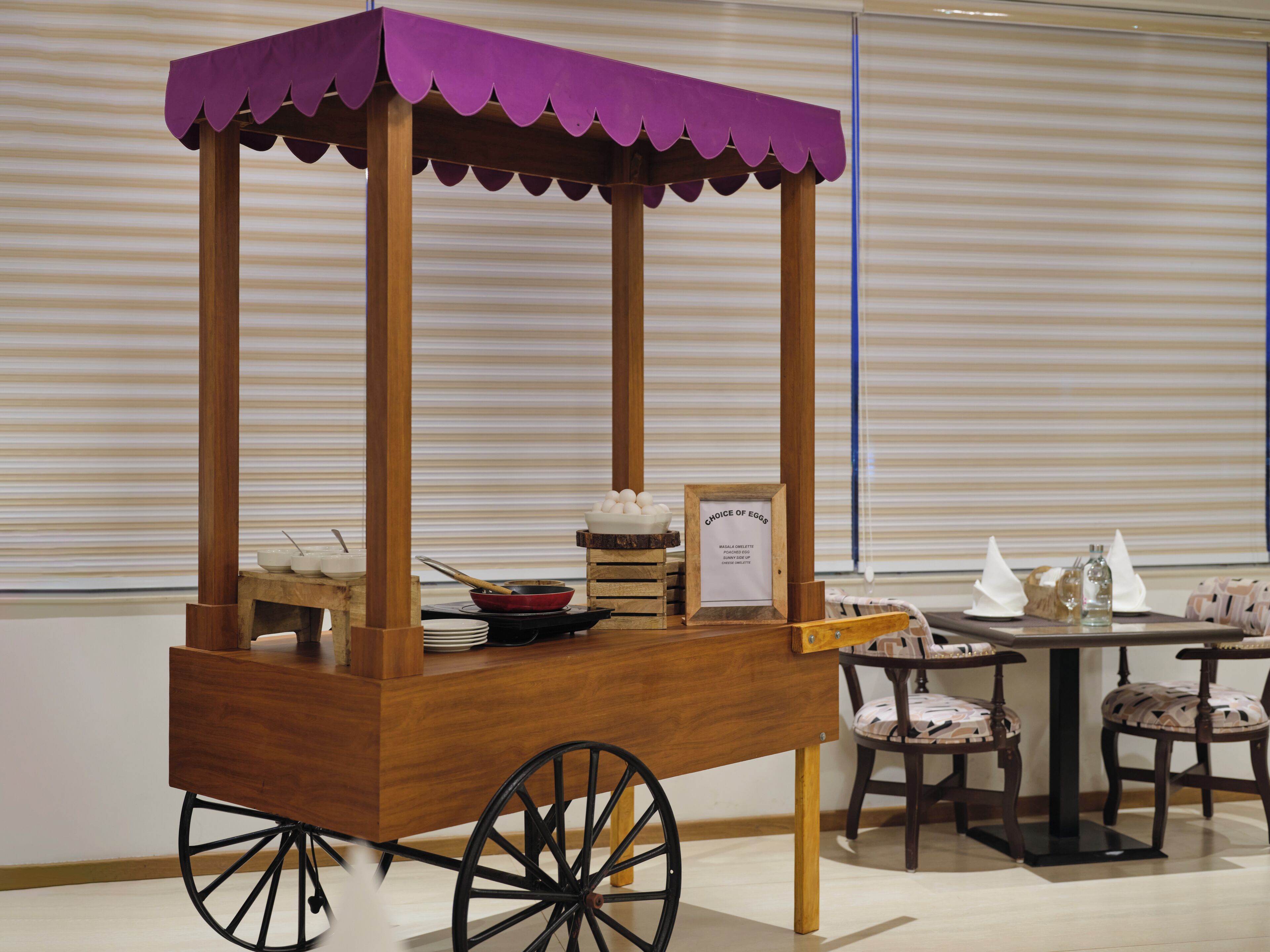 A wooden cart with a purple canopy, wheels, and a sign labeled "Choice of Eggs".