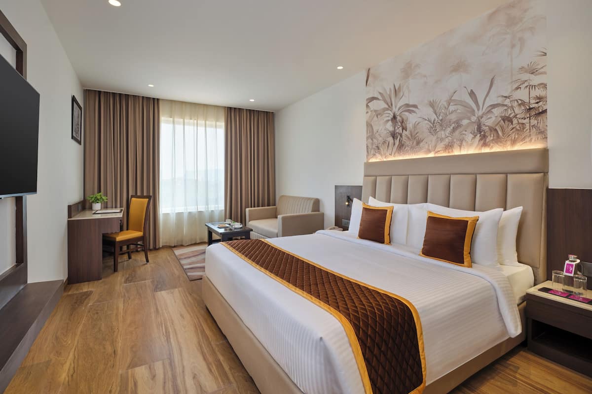 A hotel room with a large bed, a desk, a chair, and a television.