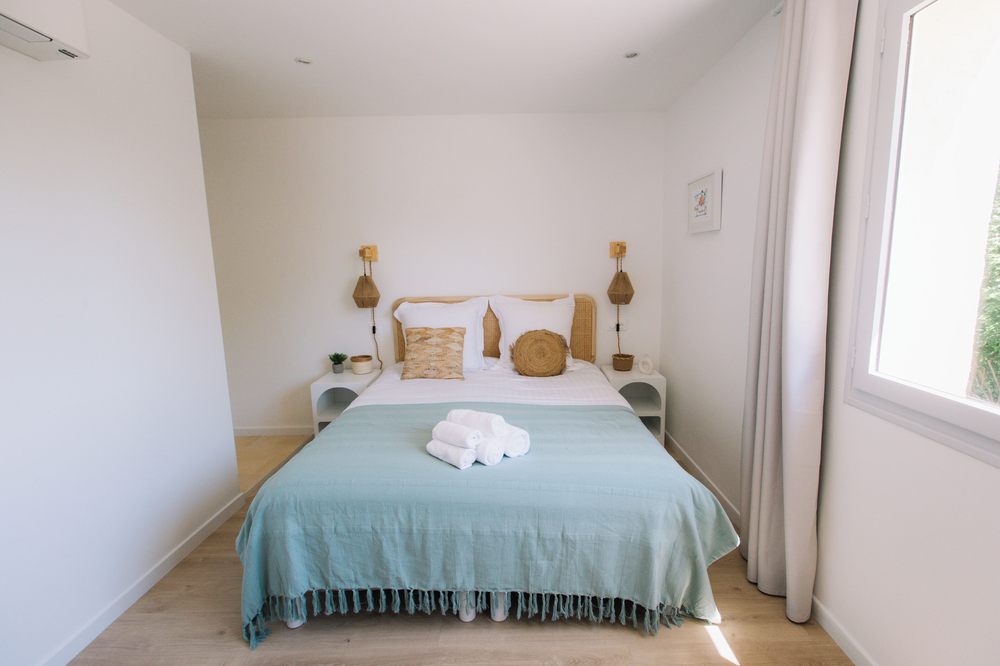 A bedroom with a bed, bedside tables, and a window.