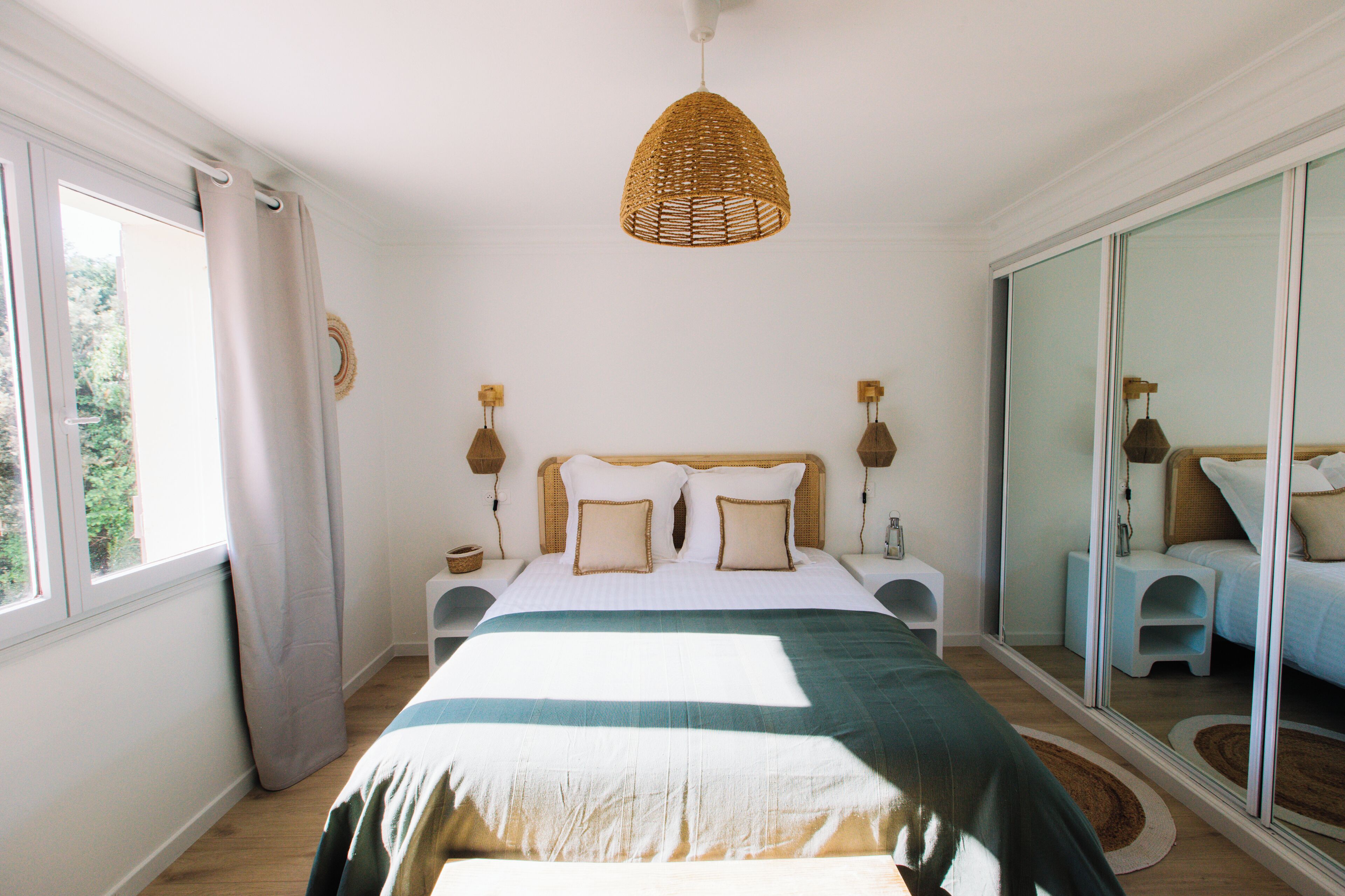 Een slaapkamer met een groot bed, een hanglamp en een schuifpui.