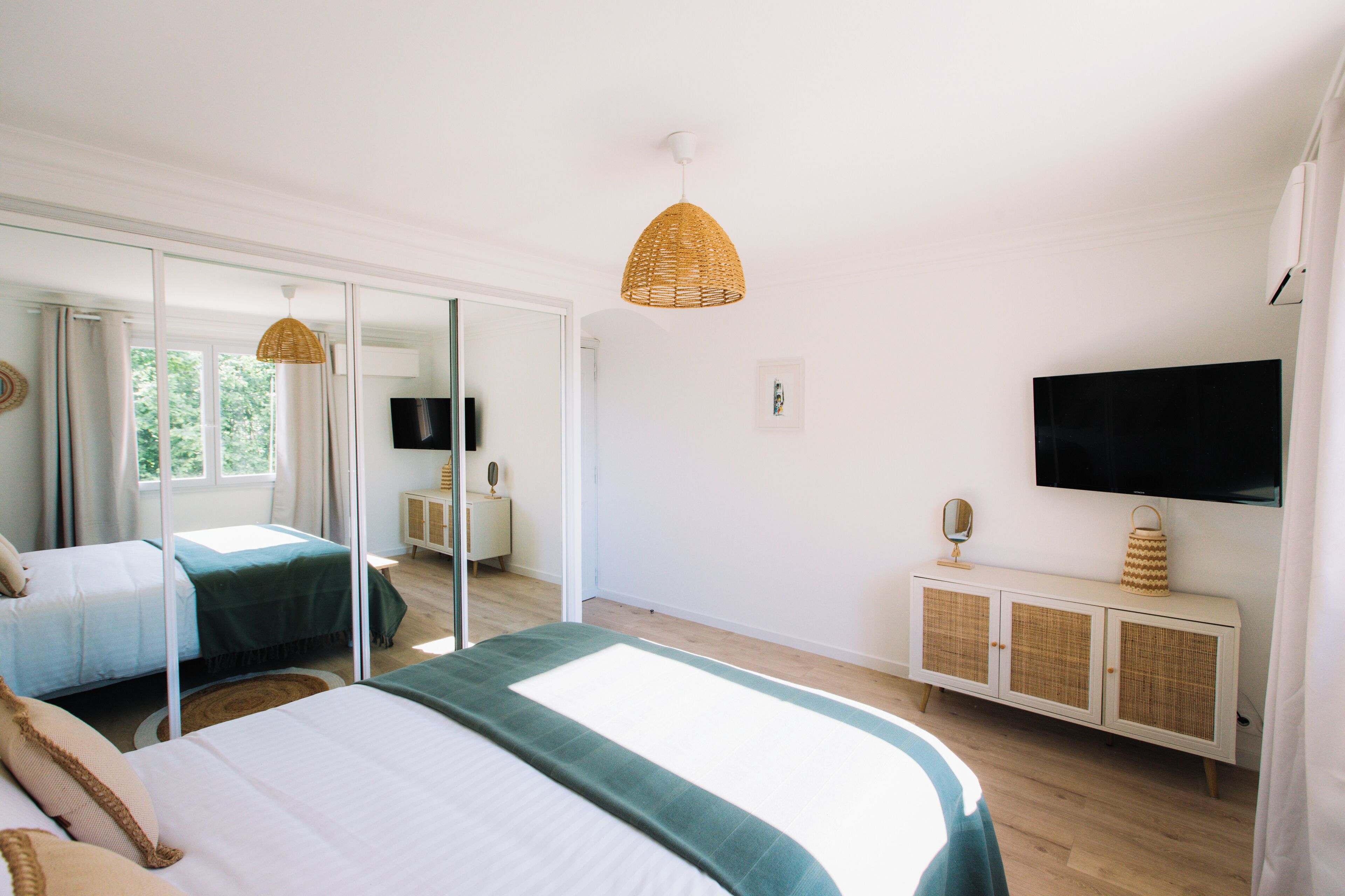 Une chambre à coucher avec un grand lit, une télévision, un miroir et une armoire.