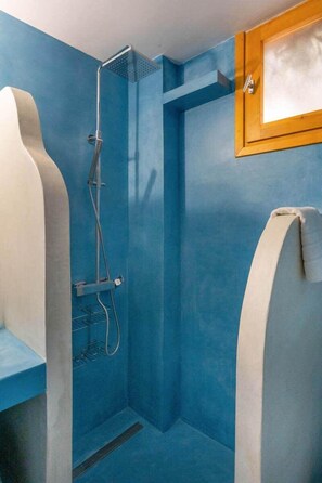 Un baño con paredes azules, una ducha y un ventanal de madera.
