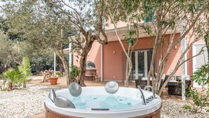 Un jacuzzi en un jardín con árboles y mobiliario exterior.