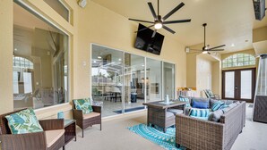 An outdoor patio area with wicker furniture, ceiling fans, and a large glass door leading to an interior space. - Game Room, Pool & Spa: Disney Area Getaway! (Haines City)