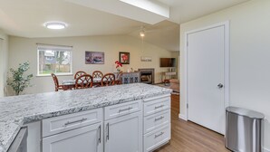 A kitchen with white cabinets, a granite countertop, and a dining area with wooden chairs.