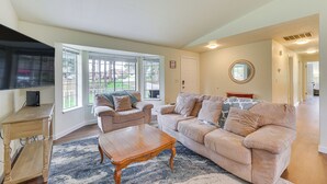A spacious living room with a large beige sofa, a wooden coffee table, and a television on a stand.
