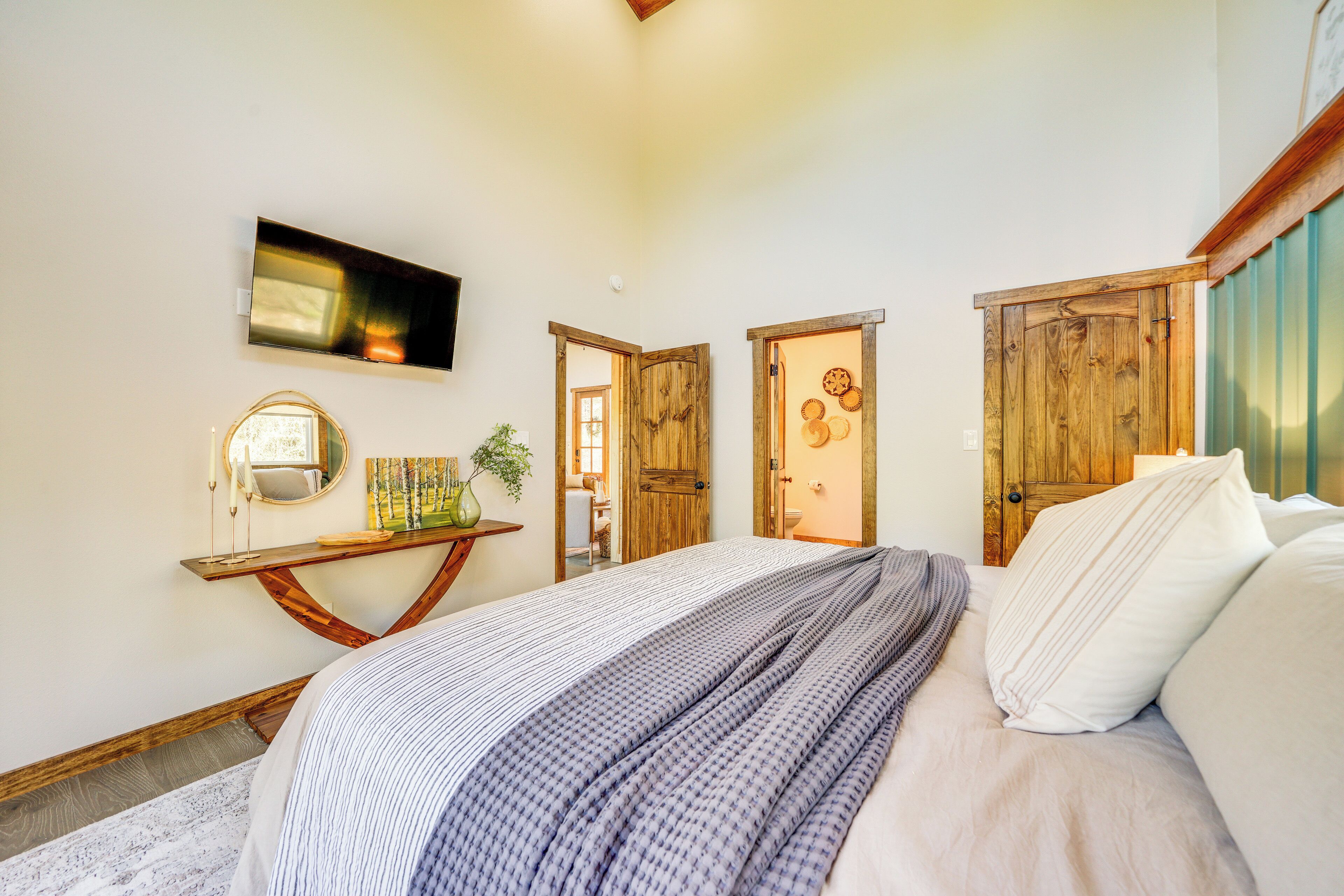 A bedroom with a bed, a television mounted on the wall, and a wooden door.