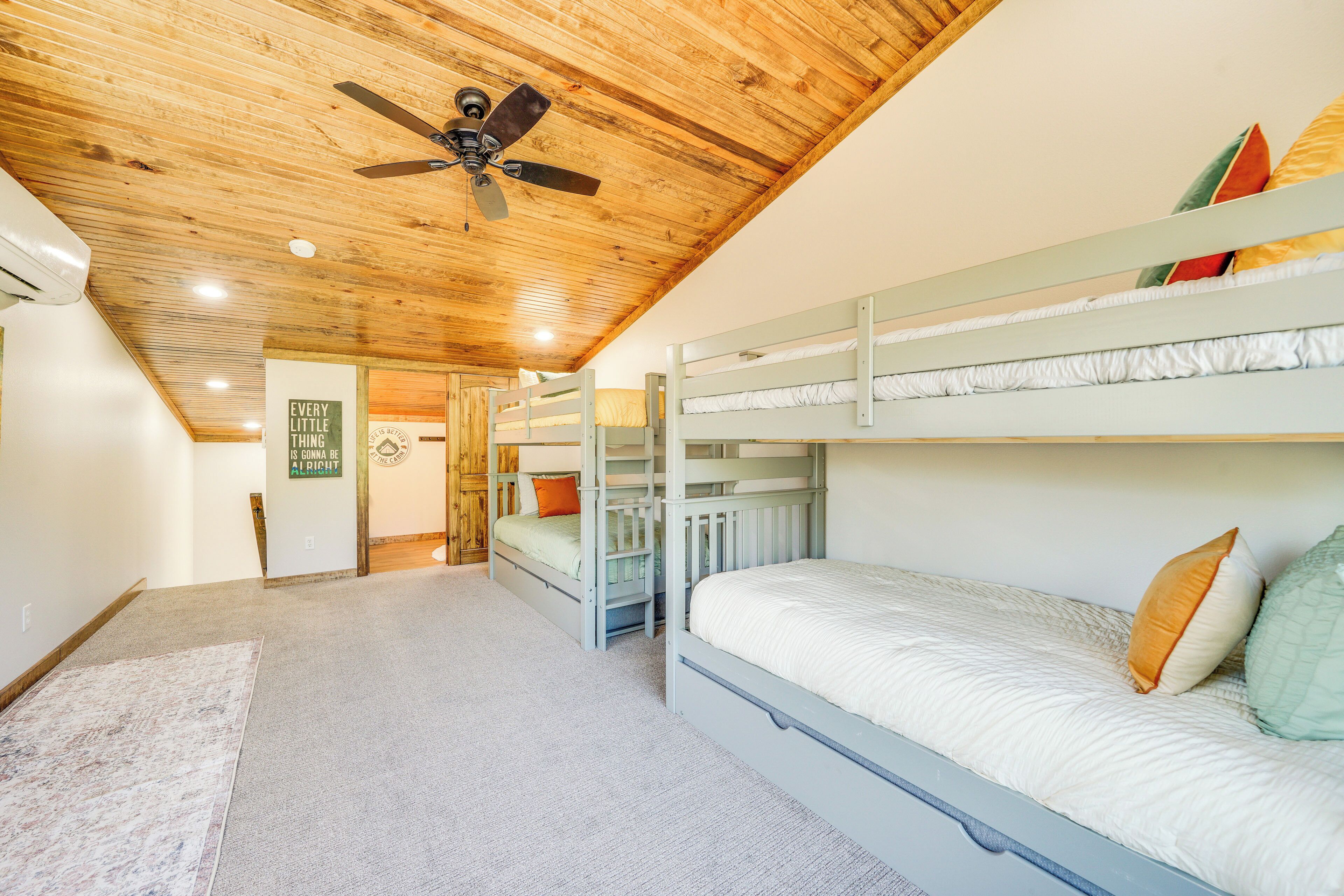 Dormitorio con literas, ventilador de techo, techo de madera y piso alfombrado.