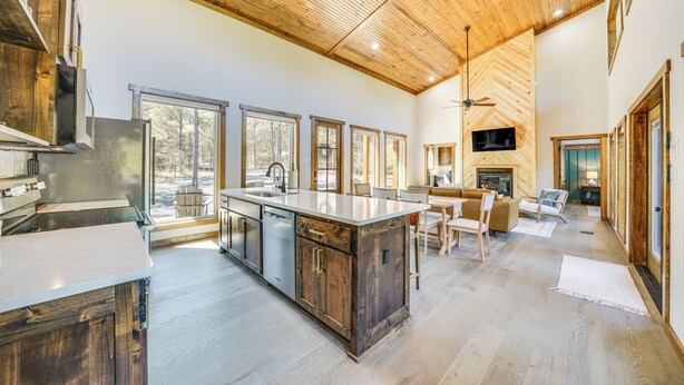 A spacious kitchen with a large island, wooden ceiling, and large windows. - Broken Bow Cabin ~ 5 Mi to State Park w/ Hot Tub! (Broken Bow)