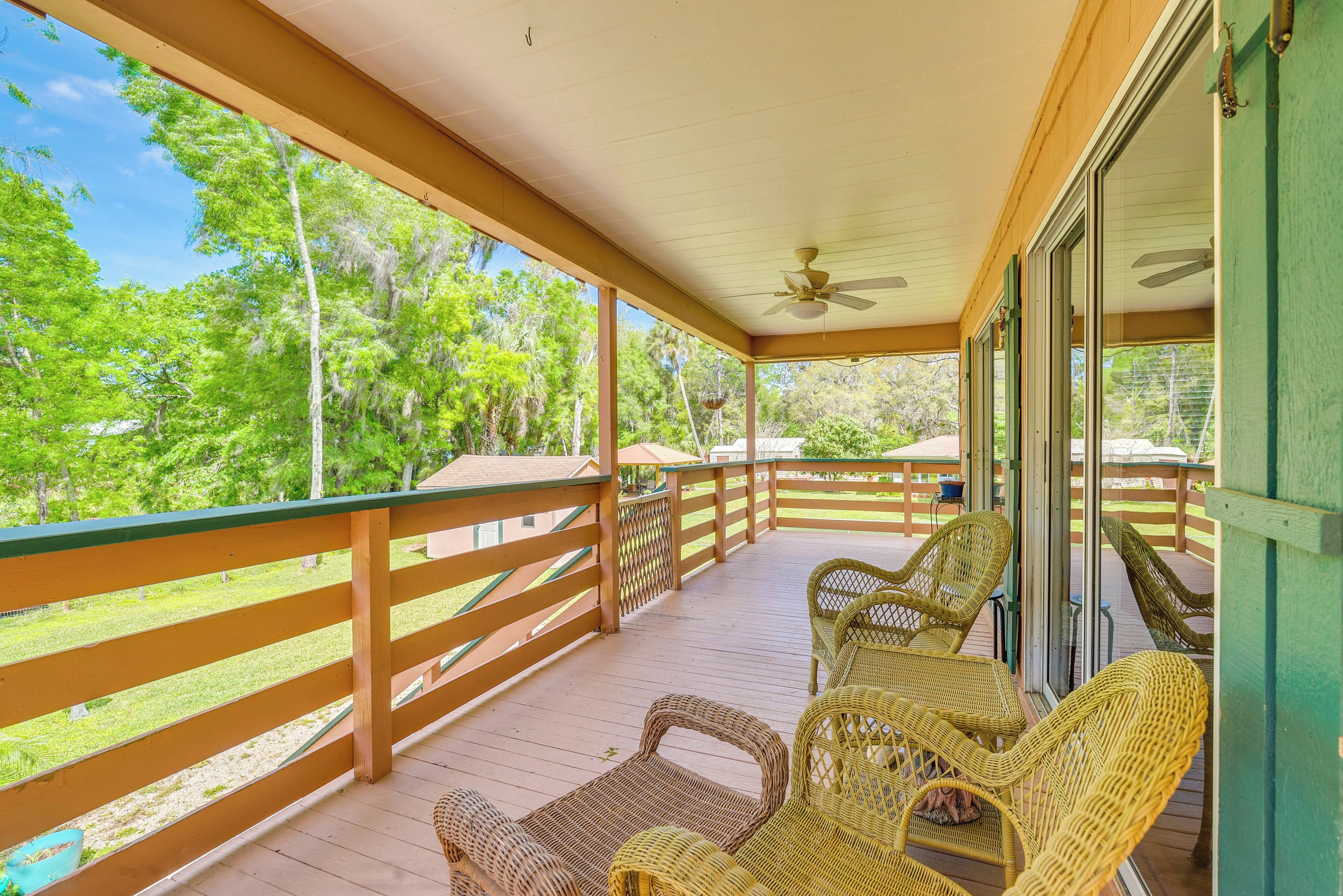 A covered porch with wicker furniture and a view of the surrounding greenery.