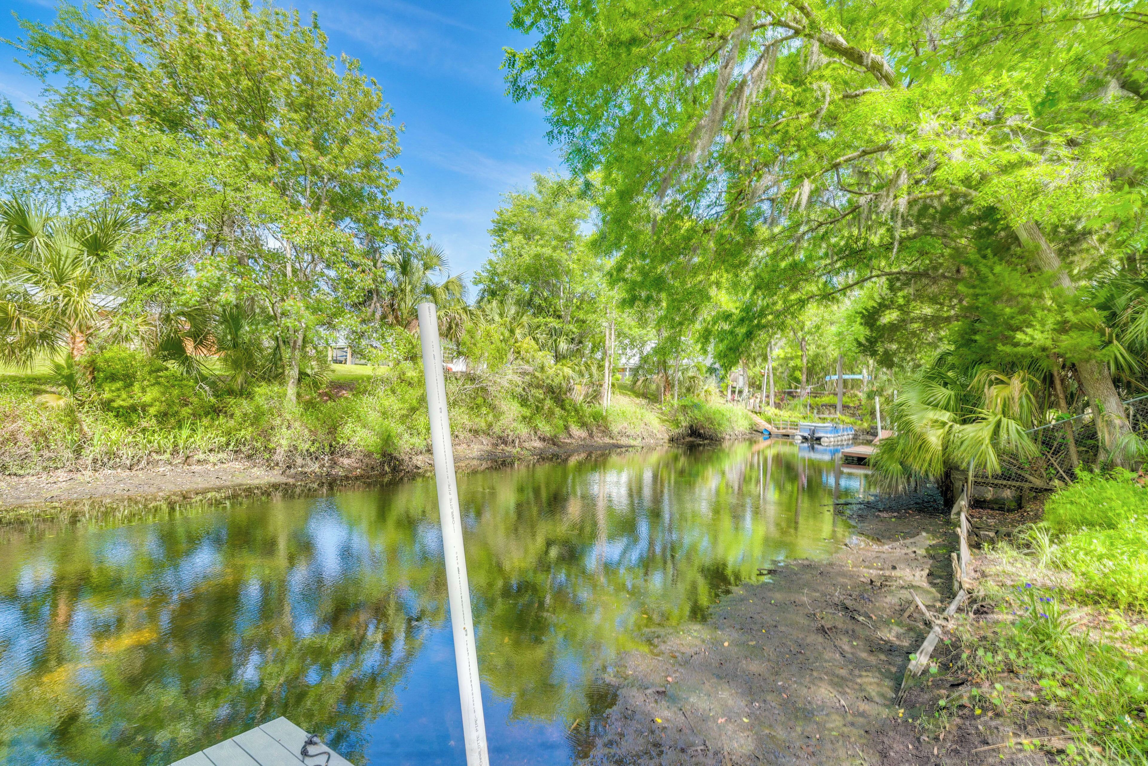 A calm river with lush greenery and a dock.