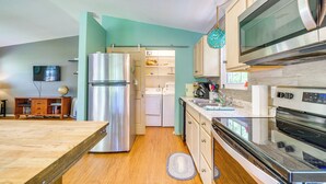 Una cocina moderna con electrodomésticos de acero inoxidable, suelo de madera y paredes verde azulado.