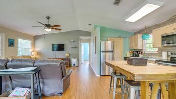 A modern kitchen with stainless steel appliances, a wooden dining table, and a bar stool.