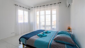 A bedroom with a bed, curtains, a window, and an air conditioning unit. - Cap Ferrat View III AP4401 By Riviera Holiday Hom (Saint-Jean-Cap-Ferrat)