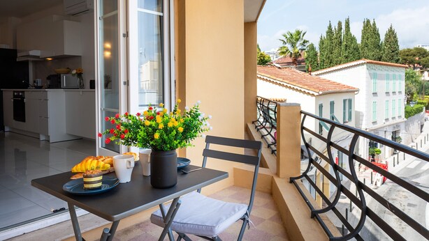 A balcony with a table, chair, and potted flowers. - Cap Ferrat View III AP4401 By Riviera Holiday Hom (Saint-Jean-Cap-Ferrat)