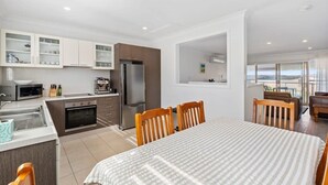 Une cuisine moderne avec des meubles blancs, un réfrigérateur et un coin repas comprenant une table et des chaises.
