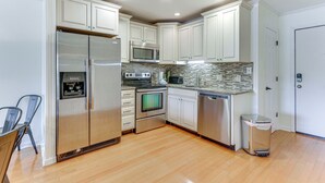 Una cocina moderna con armarios blancos, electrodomésticos de acero inoxidable y un salpicadero de azulejos.