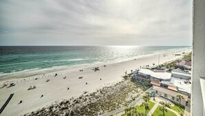 A beach with a building adjacent to it. - Oceanfront Panama City Beach Condo w/ Pool Access (Panama City Beach)