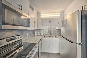 Una cucina moderna con mobili bianchi, un frigorifero in acciaio inossidabile, forno integrato e un piano di lavoro in granito.