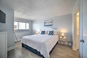 Una camera da letto con un letto grande, due comodini con lampade, una finestra con tende e un quadro appeso al muro.
