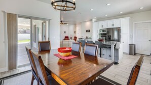 A spacious dining area with a wooden table and chairs, a chandelier, and a kitchen in the background. - Spacious Mesquite Getaway - 1/2 Mi to Golf Course (Mesquite)