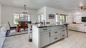 A spacious kitchen with a large island, white cabinetry, and a dining area with wooden chairs and a glass-top table. - Spacious Mesquite Getaway - 1/2 Mi to Golf Course (Mesquite)