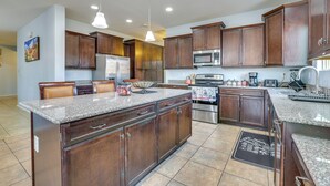 A spacious kitchen with granite countertops, dark wooden cabinets, stainless steel appliances, and pendant lighting. - Furnished Patio! Retreat 12 Mi to Dtwn Phoenix (Laveen)