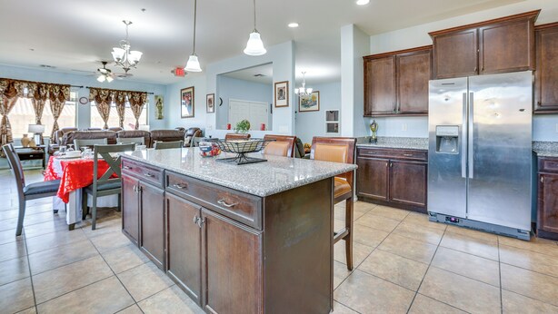 A spacious kitchen with a large island, dark wooden cabinets, stainless steel appliances, and pendant lighting. - Furnished Patio! Retreat 12 Mi to Dtwn Phoenix (Laveen)