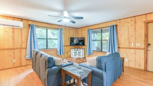 A cozy room with wooden walls, a ceiling fan, a TV, and a sofa set. - Lakefront Keystone Heights Cottage w/ Private Dock (Keystone Heights)