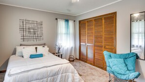 A bedroom with a bed, a blue chair, a wooden wardrobe, and a ceiling fan. - Quiet & Cozy Rembert Home ~ 9 Mi to Air Force Base (Rembert)
